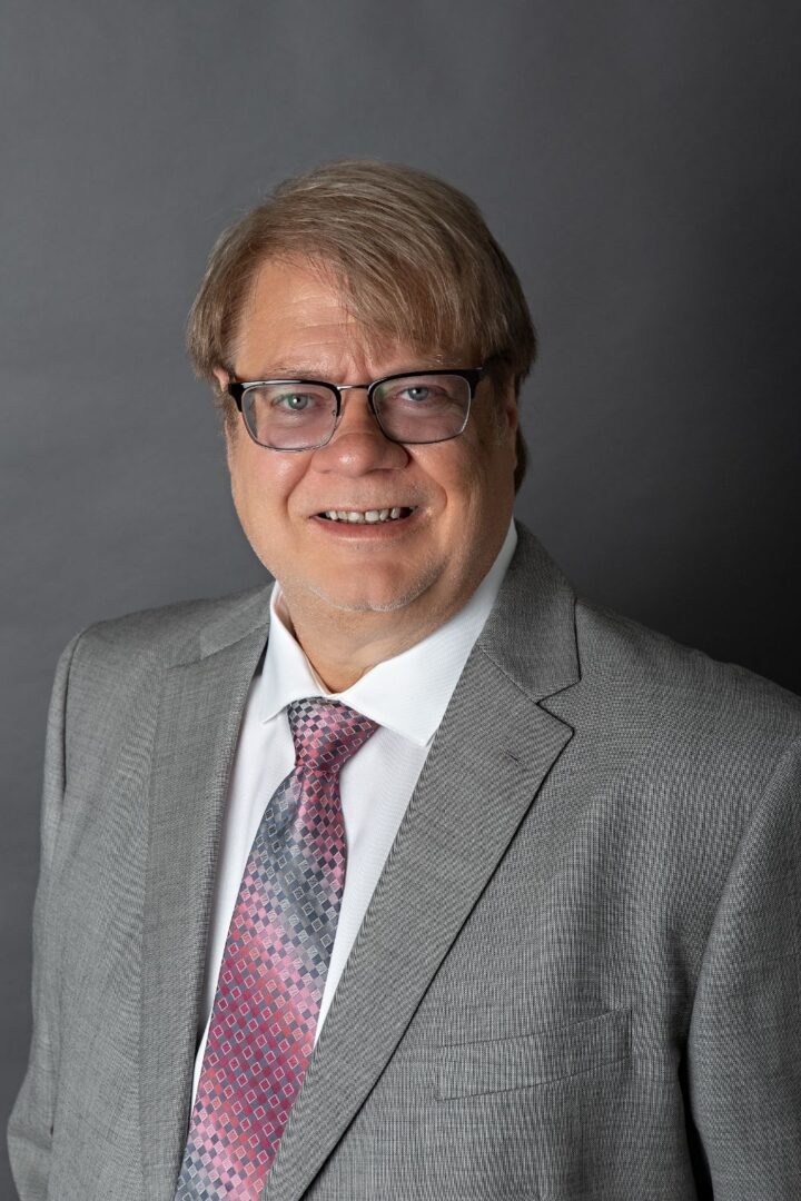 A man in a suit and tie smiling for the camera.