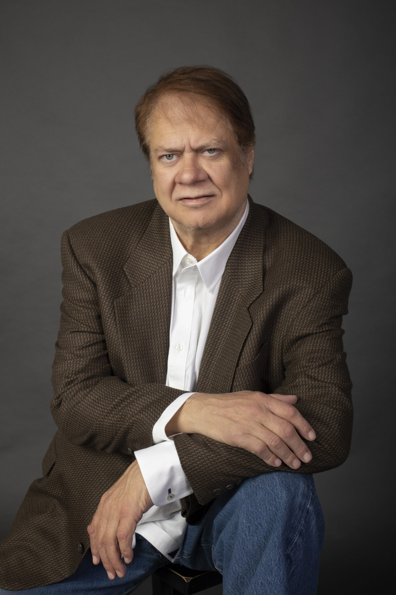 A man in brown jacket sitting on the ground.