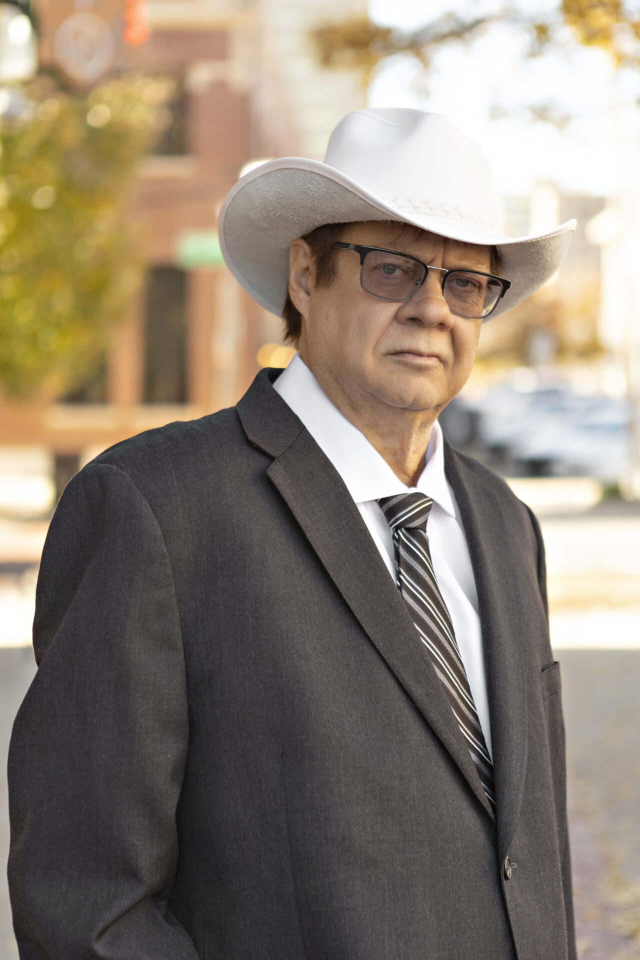 A man in a suit and hat standing on the street.