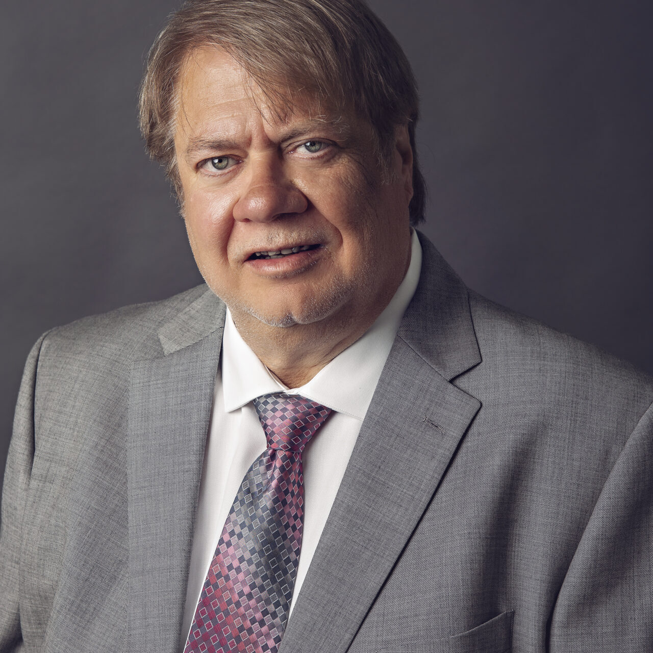 A man in a suit and tie standing up against a wall.